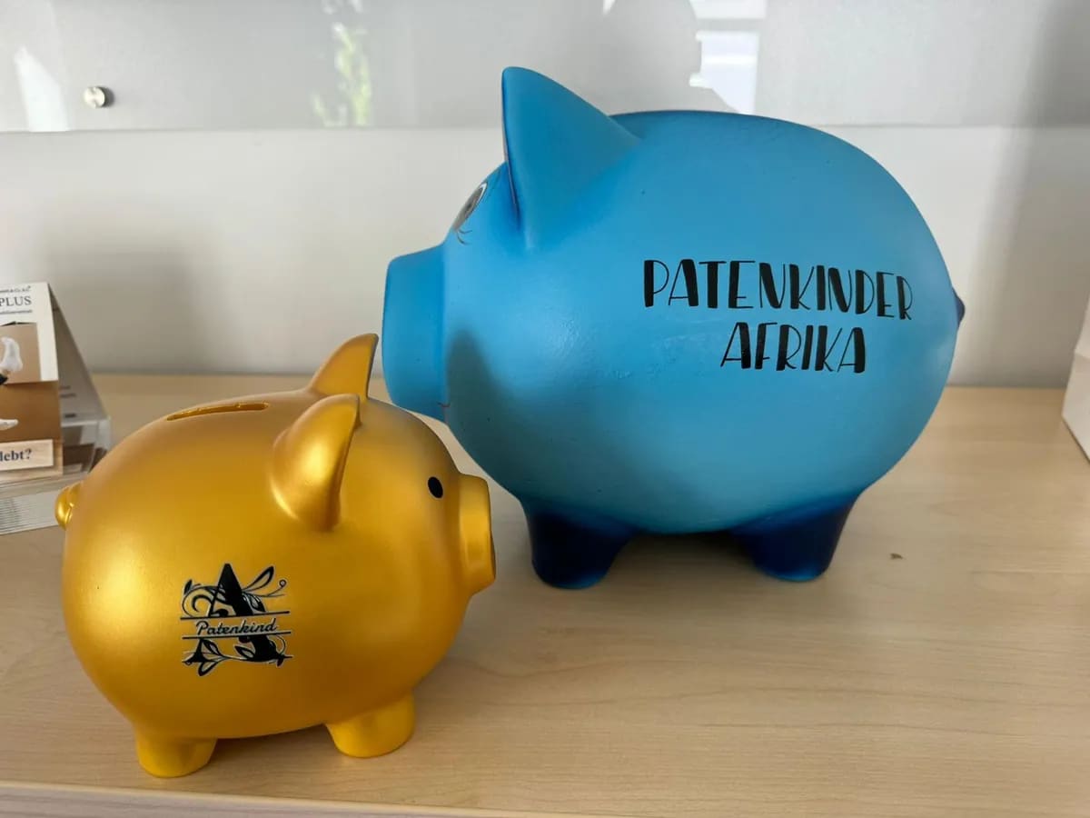 Zwei Spardosen im Primmoplus-Büro, eine mit der Aufschrift „Patenkinder Afrika“